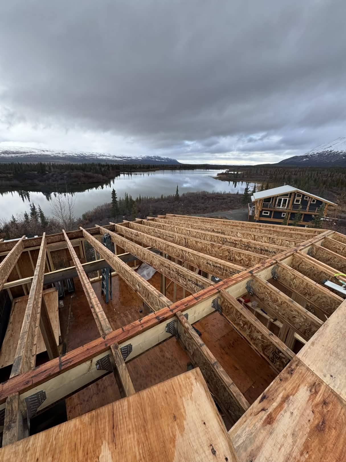 Residential frame construction overlooking lake with Alaska Range mountains, Fairbanks AK